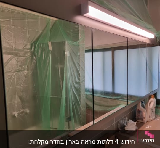 מראה גדולה עם תאורה עליונה בחדר אמבטיה